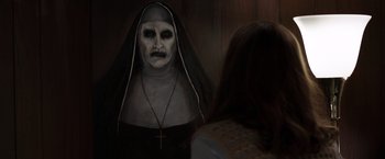 Movie still from “The Conjuring 2” (2016), directed by James Wan – A woman is looking into a mirror while a nun looks on; Close Up shot, Over the shoulder angle