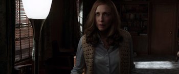 Movie still from “The Conjuring 2” (2016), directed by James Wan – A woman in a white shirt and a brown vest; Medium shot, Over the shoulder angle