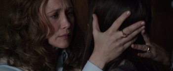 Movie still from “The Conjuring 2” (2016), directed by James Wan – A person holding a woman's hair; Close Up shot, Over the shoulder angle