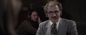 Movie still from “The Conjuring 2” (2016), directed by James Wan – A man in a suit and tie with a mustache; Close Up shot, Over the shoulder angle