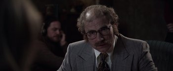 Movie still from “The Conjuring 2” (2016), directed by James Wan – An older man with a beard and mustache wearing a suit and tie; Close Up shot, Over the shoulder angle