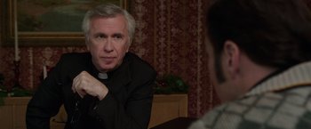 Movie still from “The Conjuring 2” (2016), directed by James Wan – An older man sitting in front of another man; Close Up shot, Over the shoulder angle