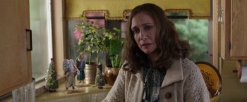 Movie still from “The Conjuring 2” (2016), directed by James Wan – A woman with long brown hair wearing a sweater and standing in front of potted plants; Close Up shot, Over the shoulder angle
