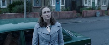 Movie still from “The Conjuring 2” (2016), directed by James Wan – A woman standing next to a car on a street; Medium shot, Over the shoulder angle