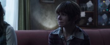 Movie still from “The Conjuring 2” (2016), directed by James Wan – A woman sitting on a couch looking to her left; Close Up shot, Over the shoulder angle