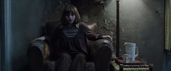 Movie still from “The Conjuring 2” (2016), directed by James Wan – A girl sitting on a chair in a room; Medium shot, High angle