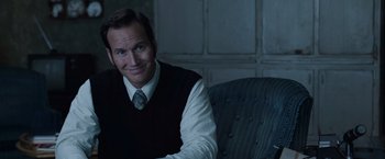 Movie still from “The Conjuring 2” (2016), directed by James Wan – A man sitting in a chair wearing a vest and tie; Close Up shot, Over the shoulder angle