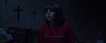 Movie still from “The Conjuring 2” (2016), directed by James Wan – A young girl in a red dress in a dark room; Medium shot, High angle