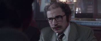 Movie still from “The Conjuring 2” (2016), directed by James Wan – A man with a beard wearing glasses and a suit and tie; Close Up shot, Over the shoulder angle