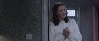 Movie still from “The Conjuring 2” (2016), directed by James Wan – A woman in a white coat smiling and clapping; Close Up shot, Over the shoulder angle