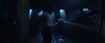 Movie still from “The Conjuring 2” (2016), directed by James Wan – A man holding a flashlight in a dark room; Medium shot, Low angle