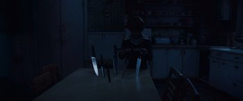 Movie still from “The Conjuring 2” (2016), directed by James Wan – A person is standing in front of a table with knives on top of it; Medium shot, High angle