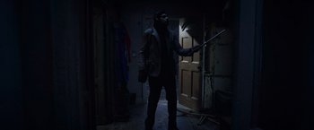 Movie still from “The Conjuring 2” (2016), directed by James Wan – A man holding a stick in a dark room; Wide shot, Low angle