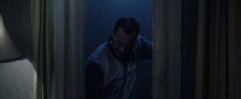 Movie still from “The Conjuring 2” (2016), directed by James Wan – A man standing in a doorway in the rain; Medium shot, Low angle
