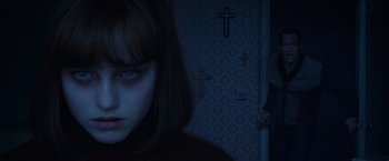 Movie still from “The Conjuring 2” (2016), directed by James Wan – A woman standing in front of a wall with crosses on it; Close Up shot, Over the shoulder angle