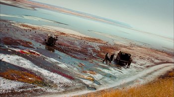 Movie still from “The Constant Gardener” (2005), directed by Fernando Meirelles – Two men are standing in the mud near a truck; Extreme Wide shot, High angle