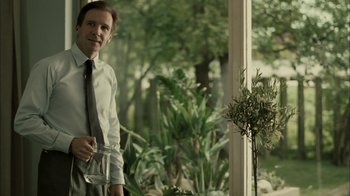 Movie still from “The Constant Gardener” (2005), directed by Fernando Meirelles – A man standing in front of a window holding a wine glass; Medium shot, Over the shoulder angle