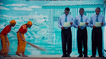 Movie still from “The Constant Gardener” (2005), directed by Fernando Meirelles – Two men standing in front of a painting of a man with a broom; Medium shot, Low angle