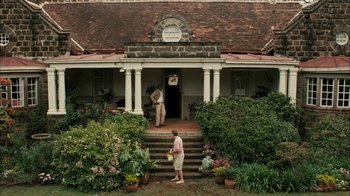 Movie still from “The Constant Gardener” (2005), directed by Fernando Meirelles – Two people standing on the front steps of a house; Wide shot, High angle