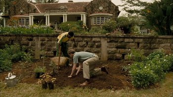 Movie still from “The Constant Gardener” (2005), directed by Fernando Meirelles – Two people working in a garden in front of a house; Wide shot, High angle