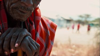 Movie still from “The Constant Gardener” (2005), directed by Fernando Meirelles – An old man wearing a red and white blanket; Extreme Close Up shot, Over the shoulder angle