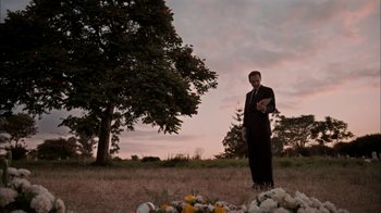 Movie still from “The Constant Gardener” (2005), directed by Fernando Meirelles – A man standing in a grassy field next to a tree; Wide shot, Low angle