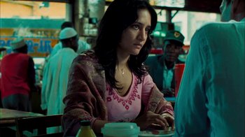 Movie still from “The Constant Gardener” (2005), directed by Fernando Meirelles – A woman sitting at a table in front of other people; Medium shot, Over the shoulder angle