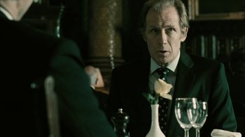 Movie still from “The Constant Gardener” (2005), directed by Fernando Meirelles – A man sitting at a table with a rose in his lapel; Close Up shot, Over the shoulder angle