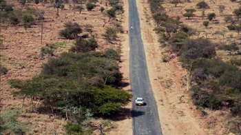 Movie still from “The Constant Gardener” (2005), directed by Fernando Meirelles – An aerial view of a car driving down a road; Extreme Wide shot, Overhead angle