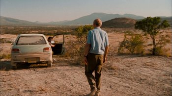 Movie still from “The Constant Gardener” (2005), directed by Fernando Meirelles – A man standing next to an open trunk of a car; Wide shot, Over the shoulder angle