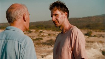 Movie still from “The Constant Gardener” (2005), directed by Fernando Meirelles – Two men standing next to each other on a dirt field; Close Up shot, Over the shoulder angle