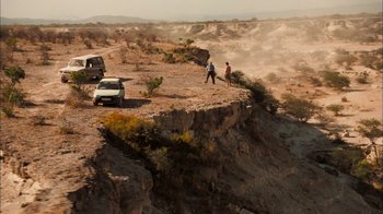 Movie still from “The Constant Gardener” (2005), directed by Fernando Meirelles – Two people standing on a cliff looking at a car; Extreme Wide shot, High angle