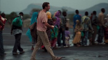 Movie still from “The Constant Gardener” (2005), directed by Fernando Meirelles – A man walking down a street with a bunch of people; Wide shot, Over the shoulder angle