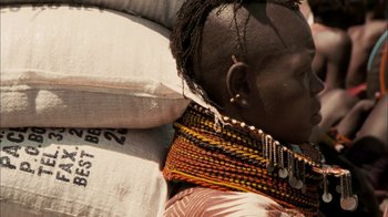 Movie still from “The Constant Gardener” (2005), directed by Fernando Meirelles – A woman wearing a colorful neck piece is laying on a pillow; Close Up shot, Over the shoulder angle