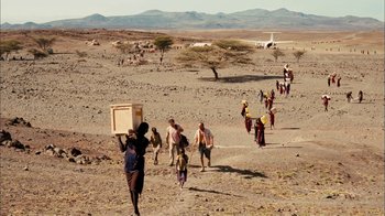 Movie still from “The Constant Gardener” (2005), directed by Fernando Meirelles – A group of people walking across a dirt field; Extreme Wide shot, High angle