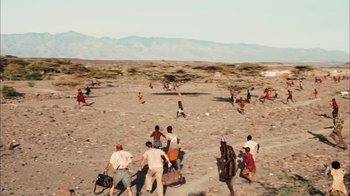 Movie still from “The Constant Gardener” (2005), directed by Fernando Meirelles – A group of people walking across a dirt field; Extreme Wide shot, High angle
