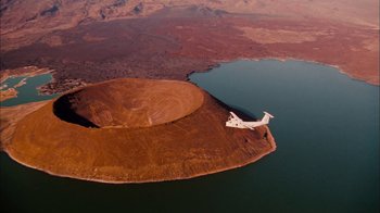 Movie still from “The Constant Gardener” (2005), directed by Fernando Meirelles – An aerial view of a plane flying over a body of water; Extreme Wide shot, Overhead angle
