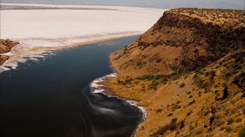 Movie still from “The Constant Gardener” (2005), directed by Fernando Meirelles – A body of water near a cliff with a body of water in the background; Extreme Wide shot, High angle