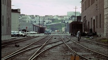 Movie still from “The Conversation” (1974), directed by Francis Ford Coppola – A man standing on the train tracks; Extreme Wide shot, High angle