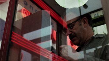 Movie still from “The Conversation” (1974), directed by Francis Ford Coppola – A man with glasses is looking at his cell phone; Close Up shot, Low angle