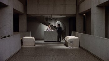Movie still from “The Conversation” (1974), directed by Francis Ford Coppola – Two men standing at a reception desk in an office building; Extreme Wide shot, High angle