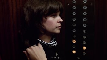 Movie still from “The Conversation” (1974), directed by Francis Ford Coppola – A woman in a black and white shirt is in a elevator; Close Up shot, Low angle