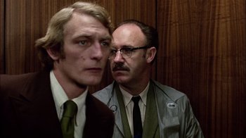 Movie still from “The Conversation” (1974), directed by Francis Ford Coppola – Two men standing next to each other in front of a wooden wall; Close Up shot, Low angle