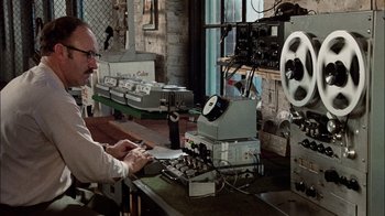 Movie still from “The Conversation” (1974), directed by Francis Ford Coppola – A man sitting in front of an old machine; Medium shot, High angle