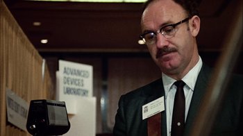 Movie still from “The Conversation” (1974), directed by Francis Ford Coppola – A man in a suit and tie looking at a cell phone; Close Up shot, Low angle