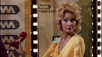 Movie still from “The Conversation” (1974), directed by Francis Ford Coppola – A woman in a yellow dress holding a red lipstick in front of a mirror; Close Up shot, Over the shoulder angle