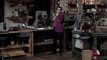 Movie still from “The Conversation” (1974), directed by Francis Ford Coppola – A man in a purple suit standing next to a table; Medium shot, High angle