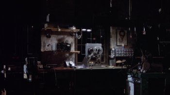 Movie still from “The Conversation” (1974), directed by Francis Ford Coppola – An old movie projector in a dark room; Wide shot, High angle