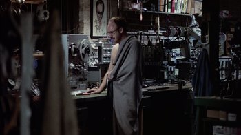 Movie still from “The Conversation” (1974), directed by Francis Ford Coppola – A man standing in front of a machine in a room; Medium shot, High angle