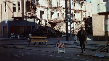 Movie still from “The Conversation” (1974), directed by Francis Ford Coppola – A man walking down a street near a building that has been demolished; Extreme Wide shot, Low angle